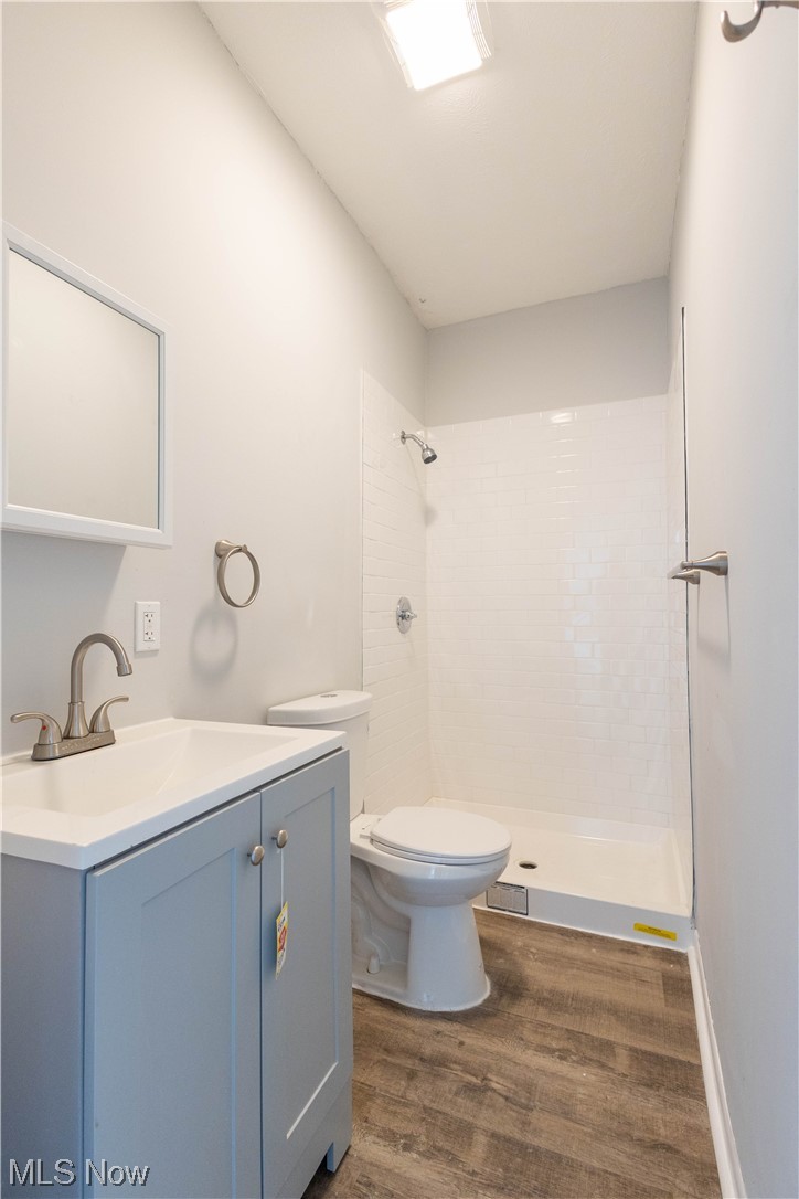 11838 Triskett Road Cleveland, OH 44111 - Photo 15 of 20 Bathroom with hardwood flooring, a tile shower, vanity with extensive cabinet space, and toilet