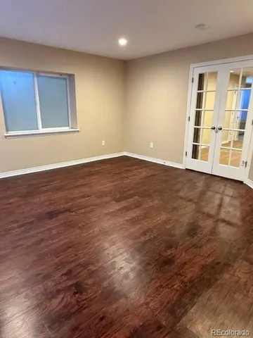a view of an empty room with wooden floor and windows
