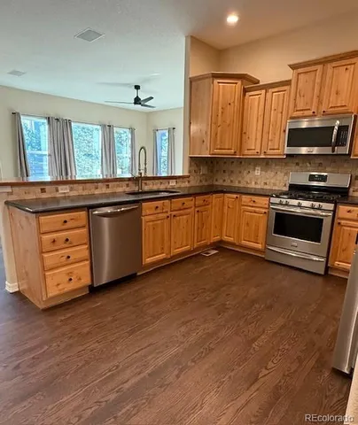 a open kitchen with granite countertop a stove top oven a sink dishwasher and cabinets with wooden floor