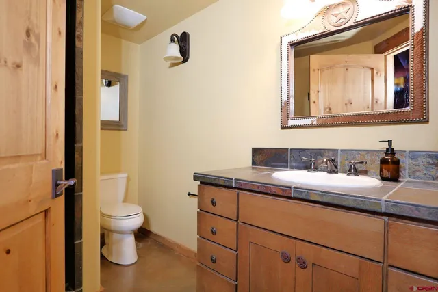a bathroom with a granite countertop toilet sink and mirror