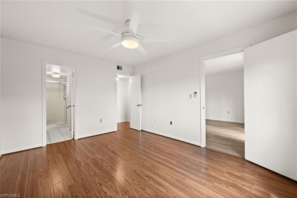 4251 27th Court Southwest, Unit 104 Naples, FL 34116 - Photo 14 of 22 an empty room with wooden floor and windows