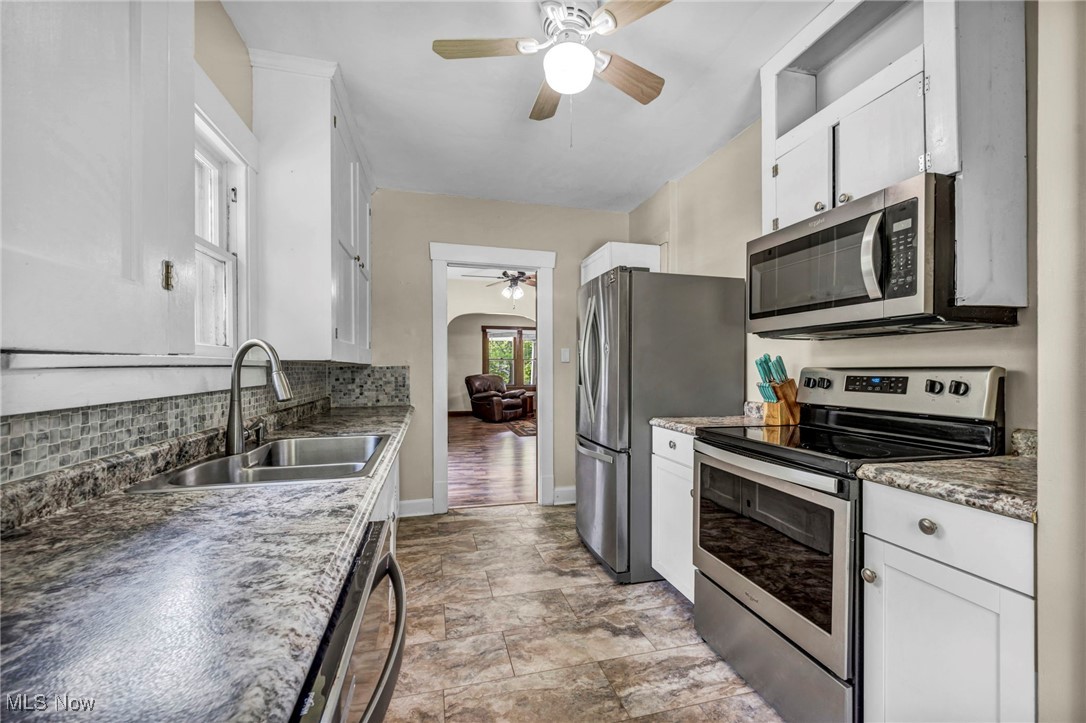 1425 Keefer Road Girard, OH 44420 - Photo 7 of 37 Kitchen with stainless steel appliances, ceiling fan, tasteful backsplash, white cabinetry, and arched walkways
