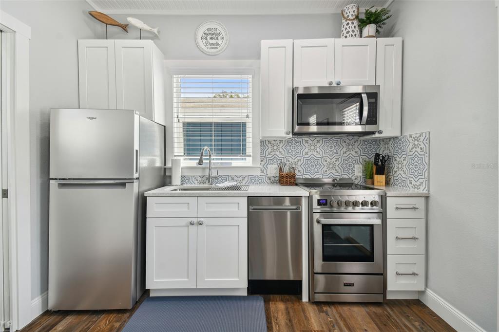 602 Skinner Boulevard Dunedin, FL 34698 - Photo 4 of 27 a kitchen with white cabinets and stainless steel appliances