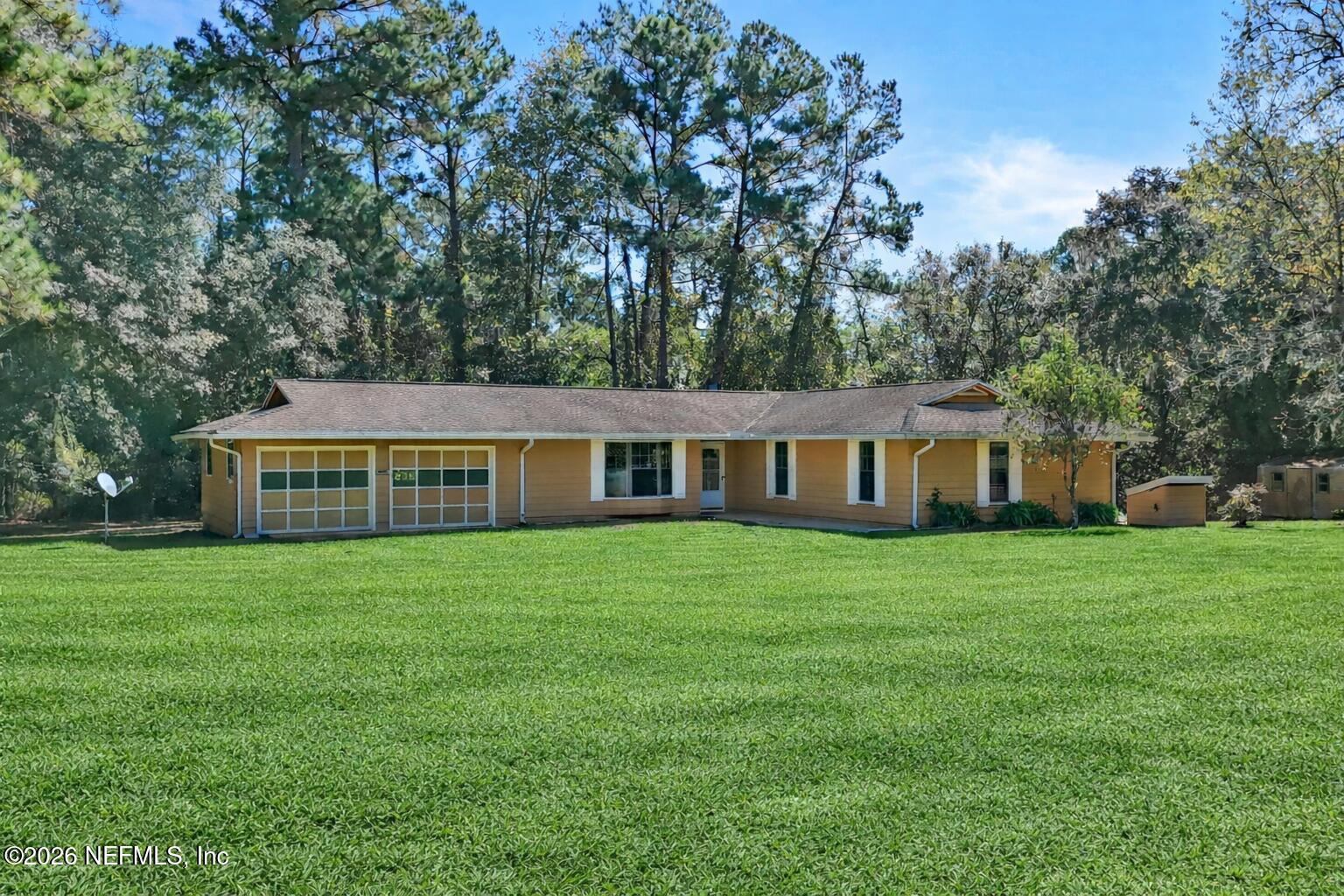 1733 Hereford Road Middleburg, FL 32068 - Photo 2 of 44 a house that is sitting in the grass with large trees and plants