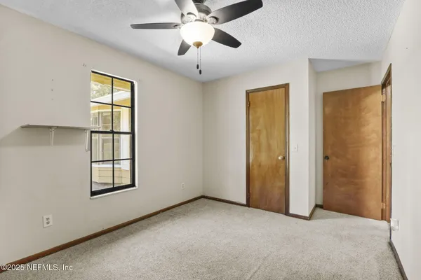 an empty room with windows and ceiling fan