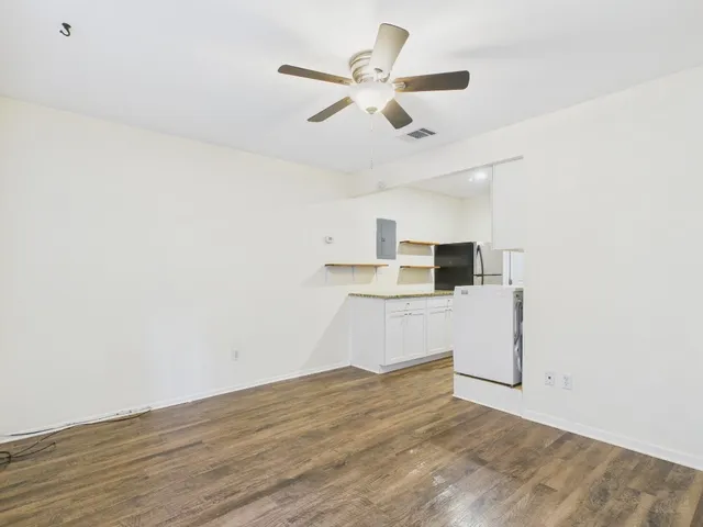 a view of kitchen and empty room with wooden floor