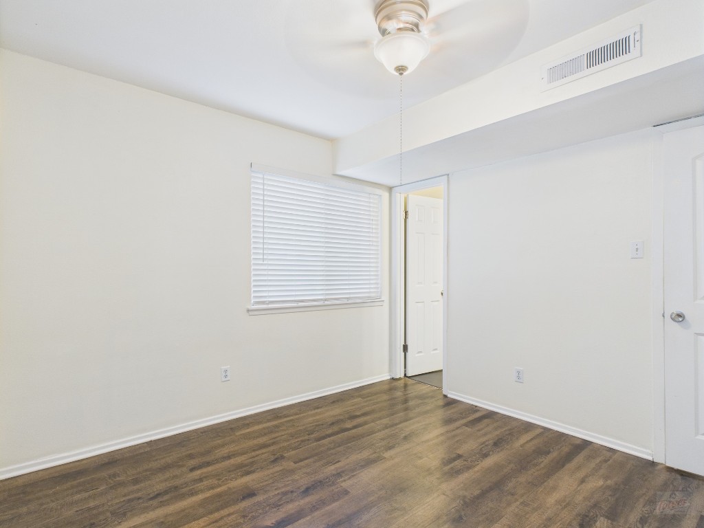 1106 West 22nd Street, Unit 5 Austin, TX 78705 - Photo 8 of 15 an empty room with wooden floor chandelier fan and windows