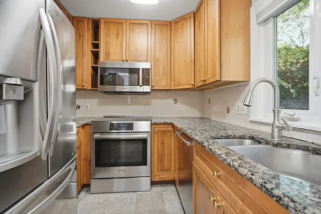 a kitchen with granite countertop a sink stainless steel appliances and cabinets
