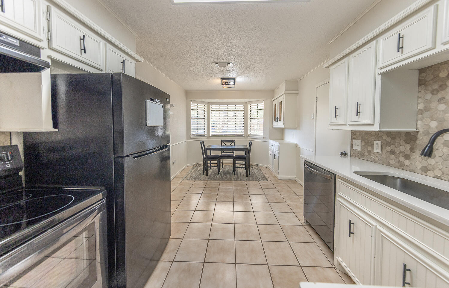 4706 78th Street Lubbock, TX 79424 - Photo 11 of 43 a kitchen with granite countertop a refrigerator stove top oven and sink