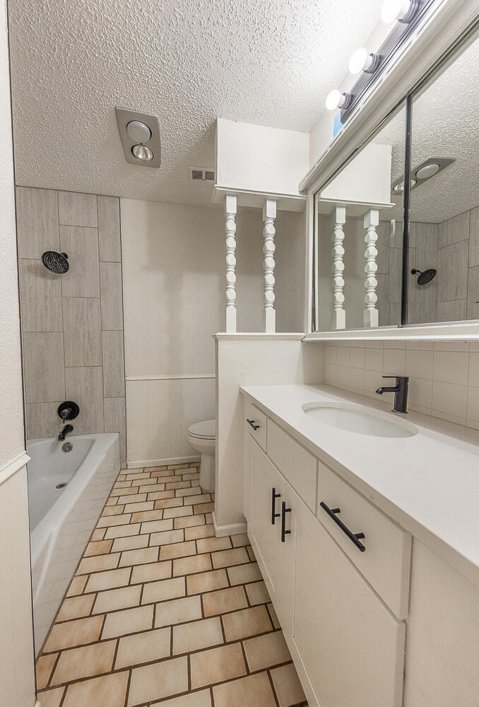 4706 78th Street Lubbock, TX 79424 - Photo 22 of 43 a bathroom with a sink a toilet a mirror and next to a window