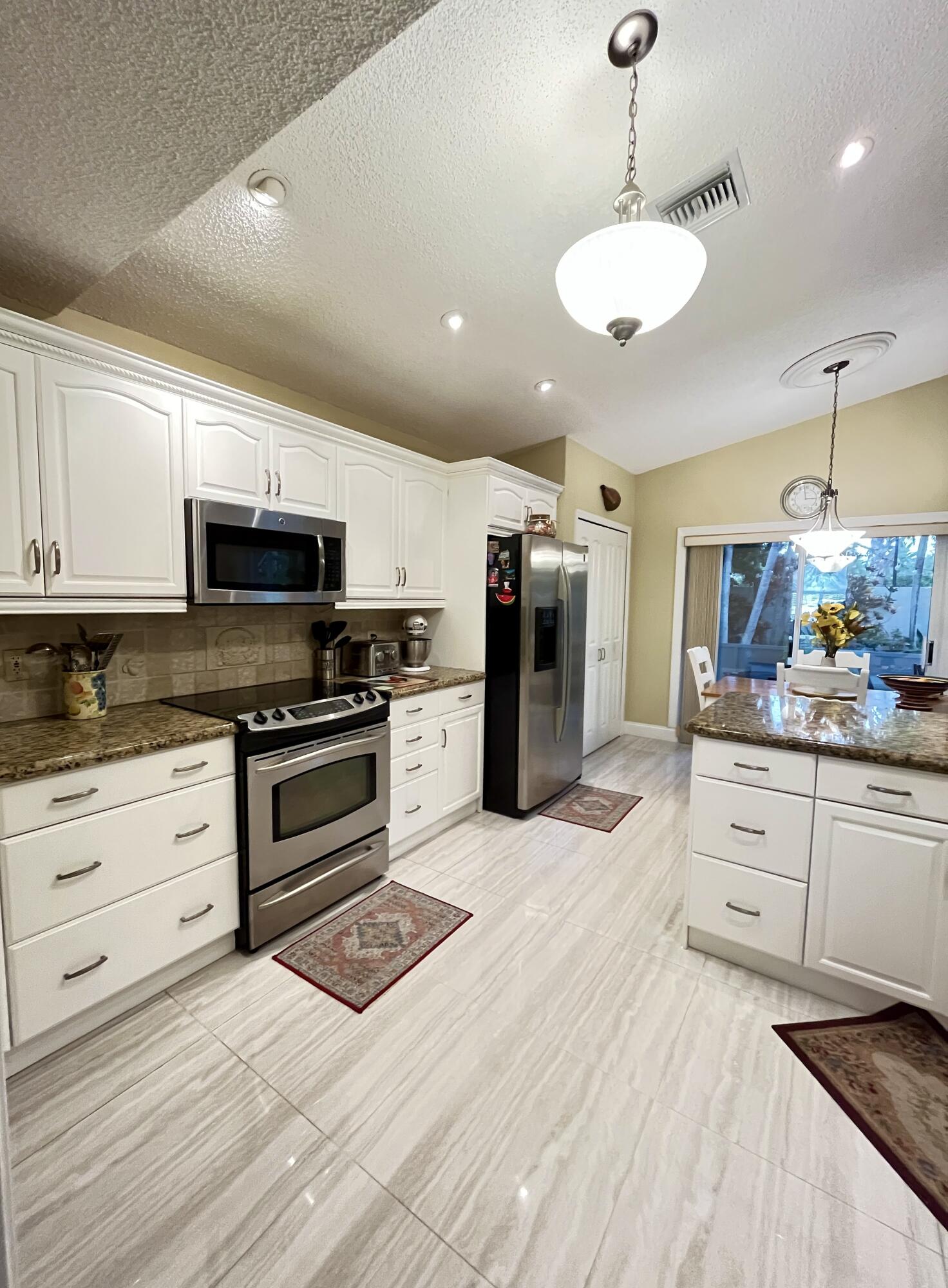 151 St Michaels Court Jupiter, FL 33458 - Photo 14 of 41 a kitchen with stainless steel appliances kitchen island granite countertop a stove a sink and a refrigerator