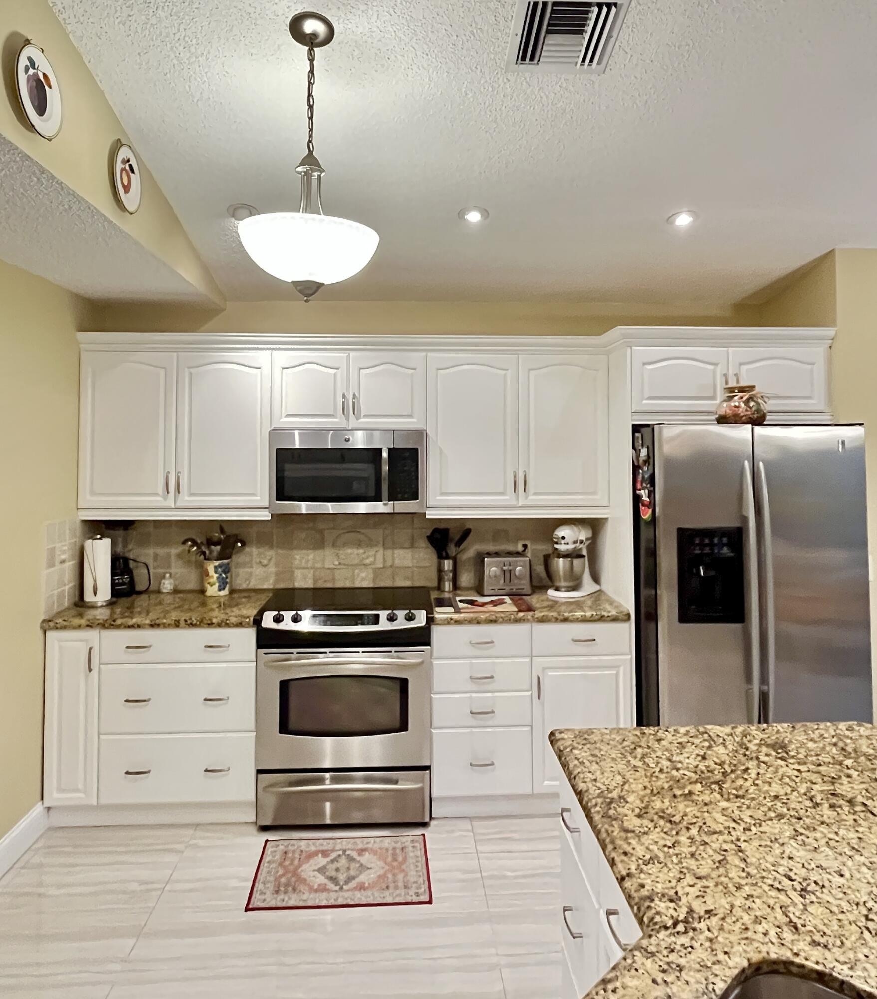 151 St Michaels Court Jupiter, FL 33458 - Photo 15 of 41 a kitchen with stainless steel appliances granite countertop a stove top oven a refrigerator a sink and a dining table with wooden floor