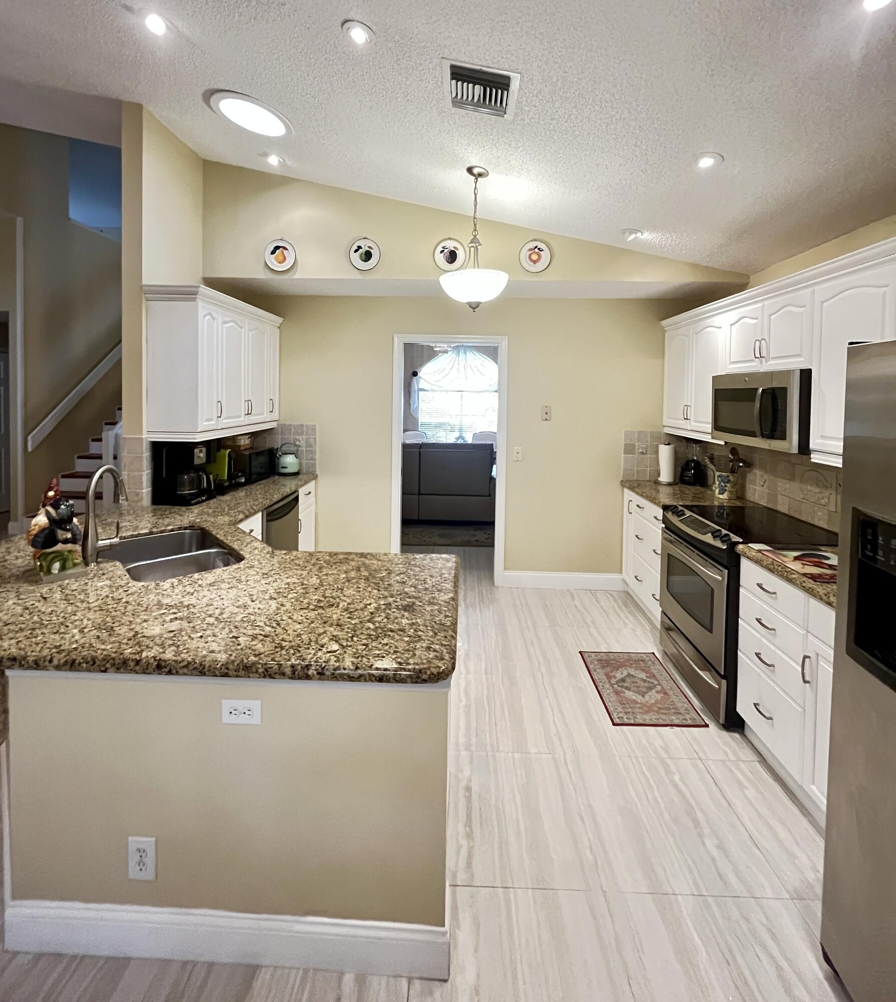 151 St Michaels Court Jupiter, FL 33458 - Photo 16 of 41 a kitchen with stainless steel appliances granite countertop a sink a stove and a wooden floors