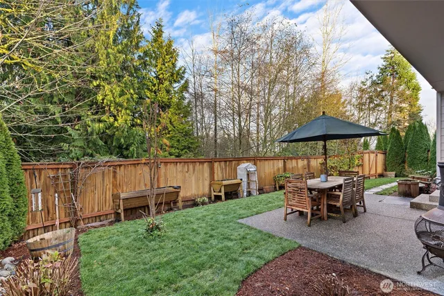 a view of backyard with table and chairs under an umbrella with wooden fence