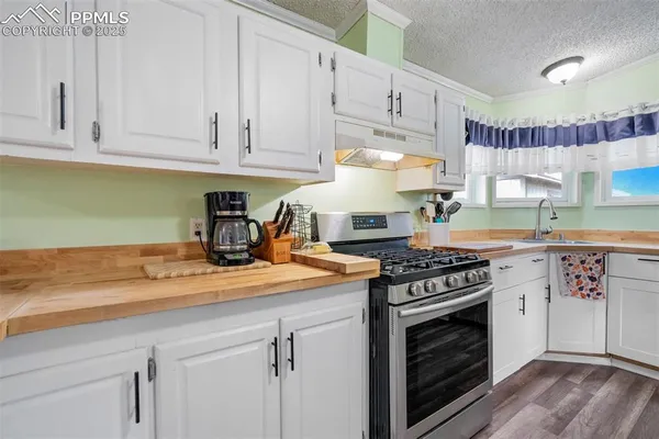 a kitchen with granite countertop a stove top oven a sink and cabinets