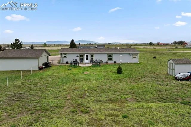 a view of a lake with lawn chairs and large trees