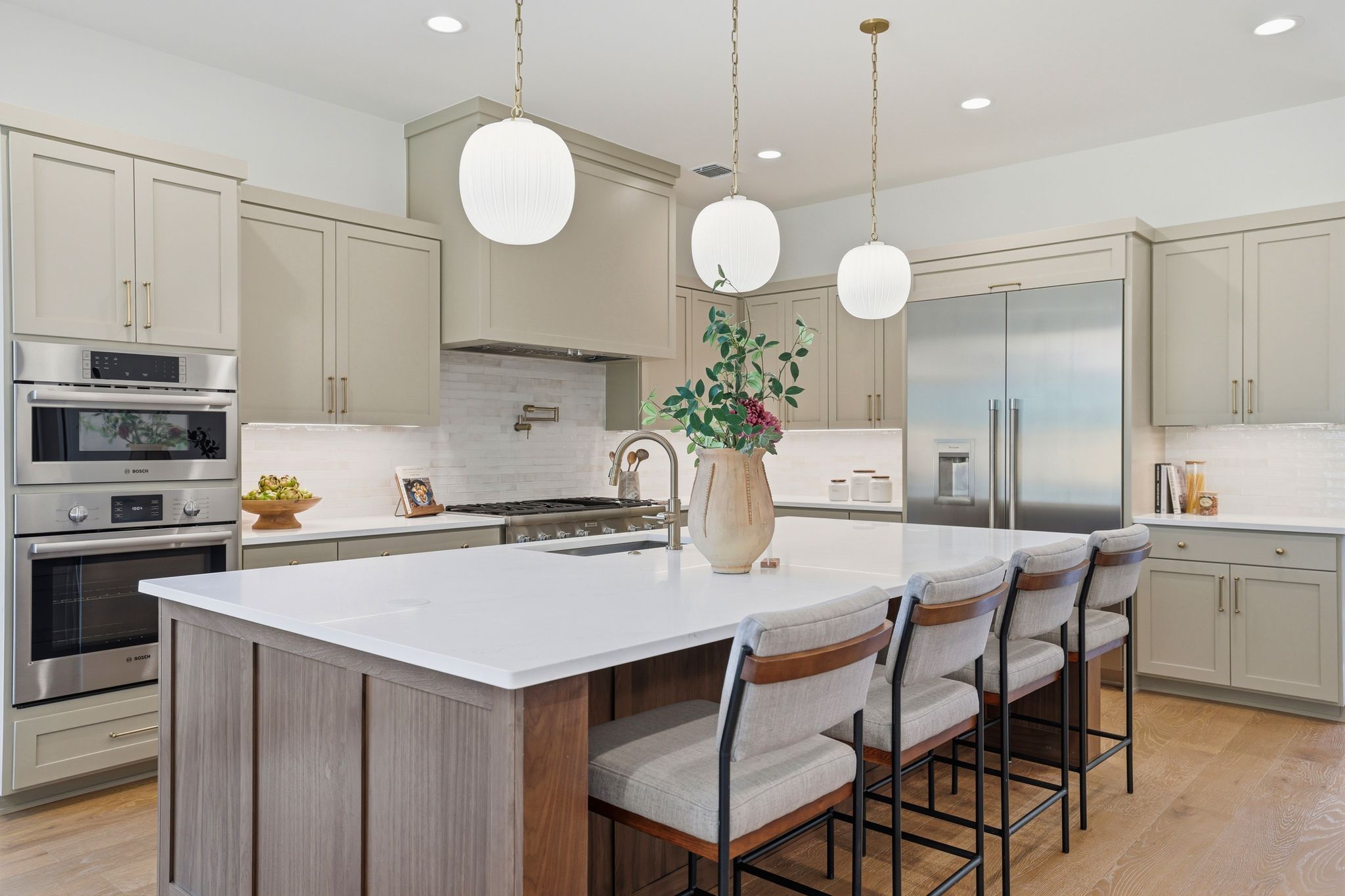 4500 Jinx Avenue Austin, TX 78745 - Photo 13 of 40 Kitchen with stainless steel appliances, decorative light fixtures, backsplash, a center island with sink, and light wood-type flooring