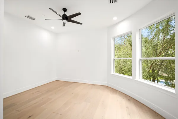 an empty room with windows and ceiling fan