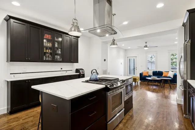a kitchen with a stove a sink a kitchen island with wooden cabinets and wooden floor