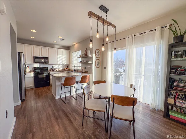 a living room with stainless steel appliances furniture and a wooden floor