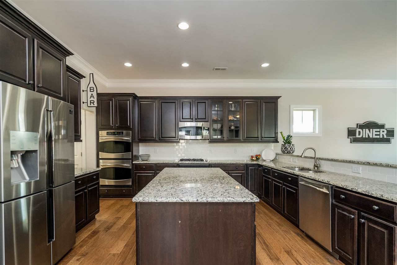 1400 Van Page Boulevard Raleigh, NC 27607 - Photo 12 of 30 Granite, SS appliances, bar for seating, double ovens, hardwoods, oversized island, subway tile backsplash, gas cooktop all in this open kitchen for cooking and entertaining! Kitchen