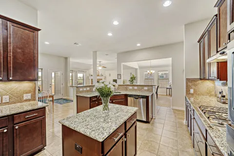 a kitchen with stainless steel appliances granite countertop table chairs sink and stove