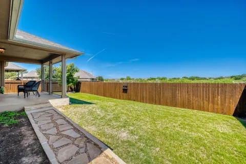 a view of a backyard with lawn chairs under an umbrella