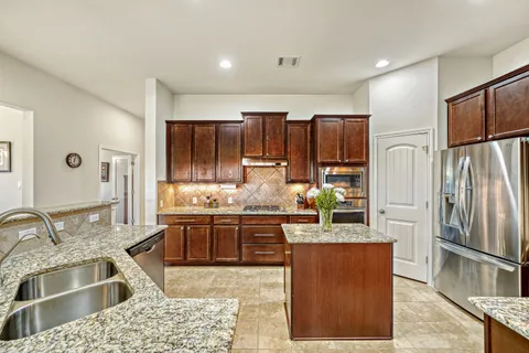 a kitchen with stainless steel appliances granite countertop a refrigerator and a sink