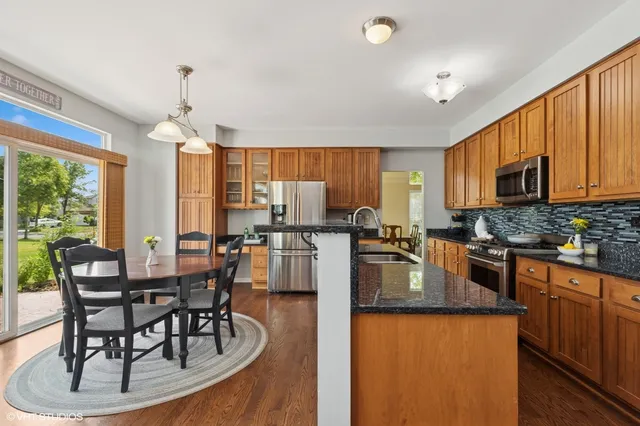 a kitchen with granite countertop a stove a sink a dining table and chairs