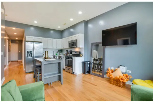 a living room with stainless steel appliances furniture and a flat screen tv