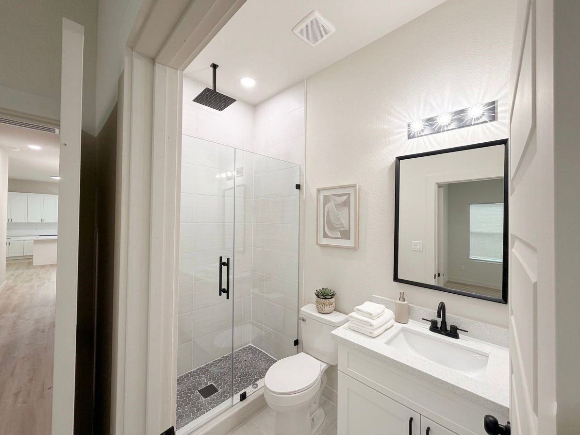 9736 Garcroft Street Houston, TX 77029 - Photo 12 of 17 a bathroom with a toilet a sink a mirror a shower and vanity