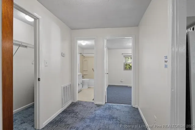 hallway view with wooden floor and a bathroom