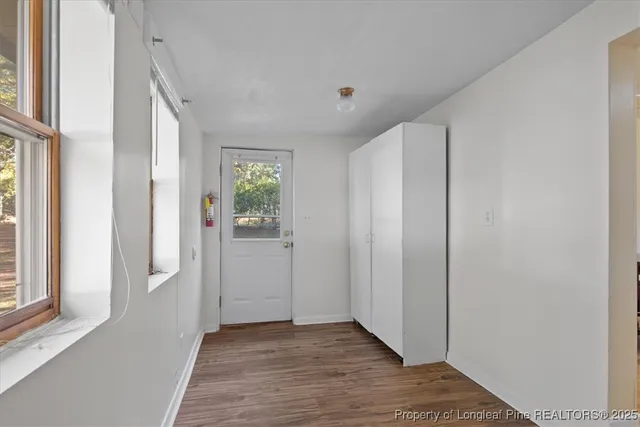 a view of an empty room with wooden floor and a window