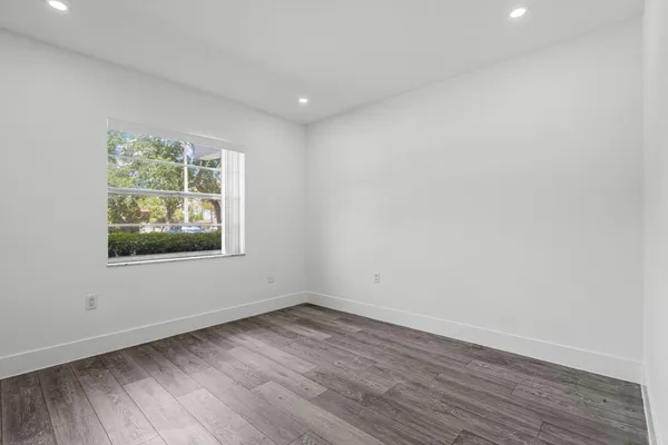a view of an empty room with wooden floor and a window