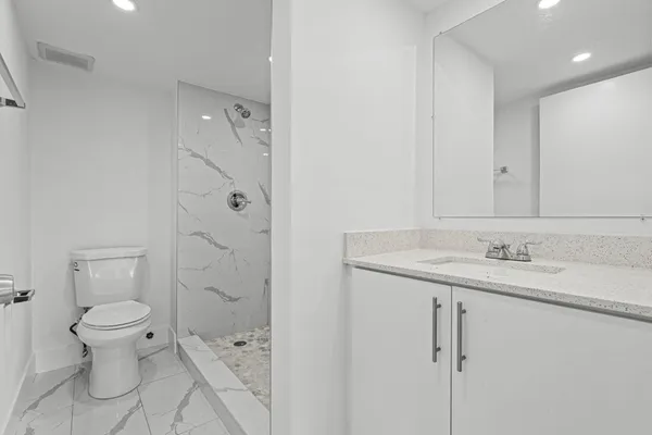 a bathroom with a granite countertop sink a toilet and shower