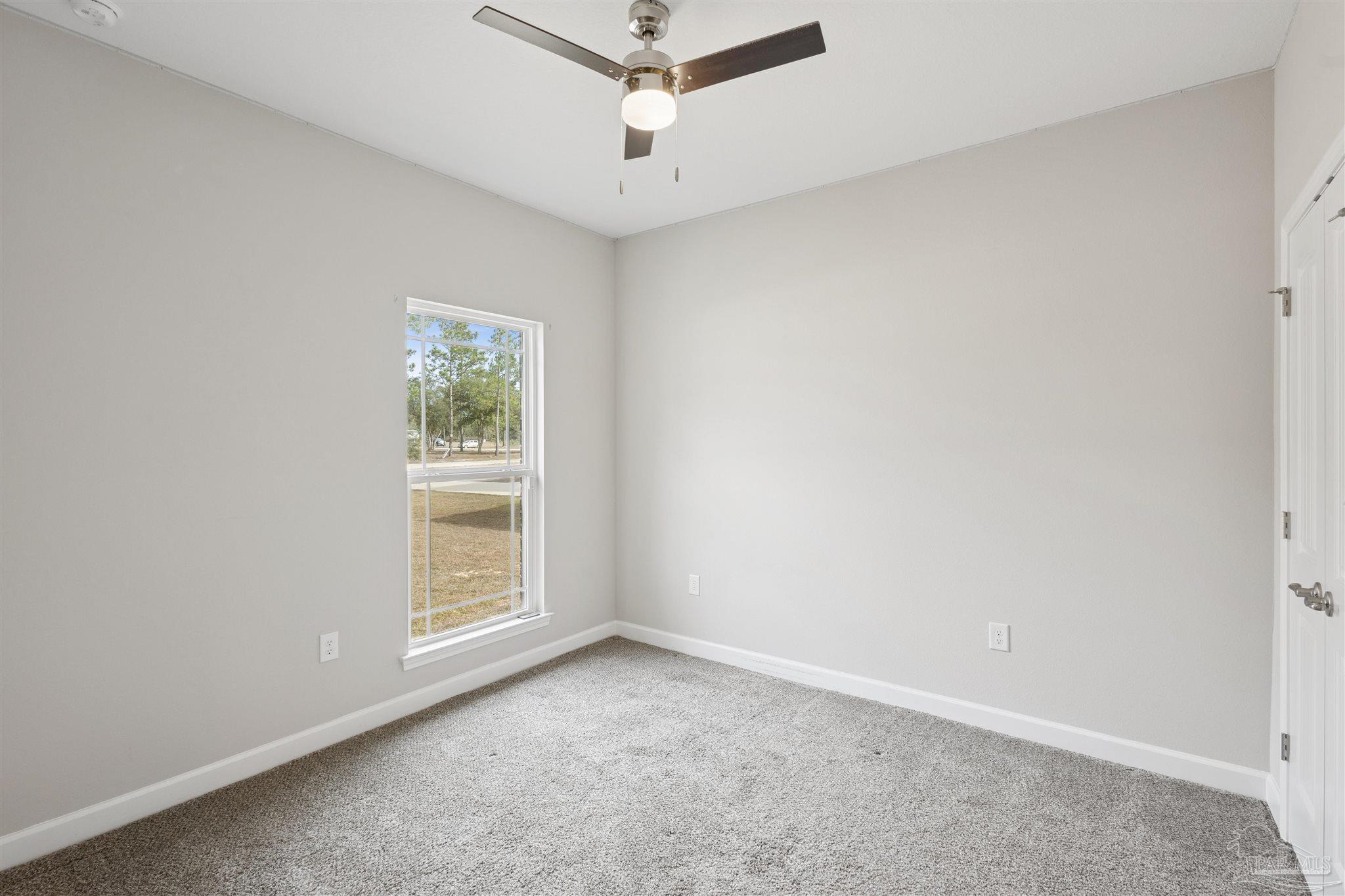 9855 Shangri La West Road Milton, FL 32583 - Photo 26 of 32 an empty room with a window and a ceiling fan