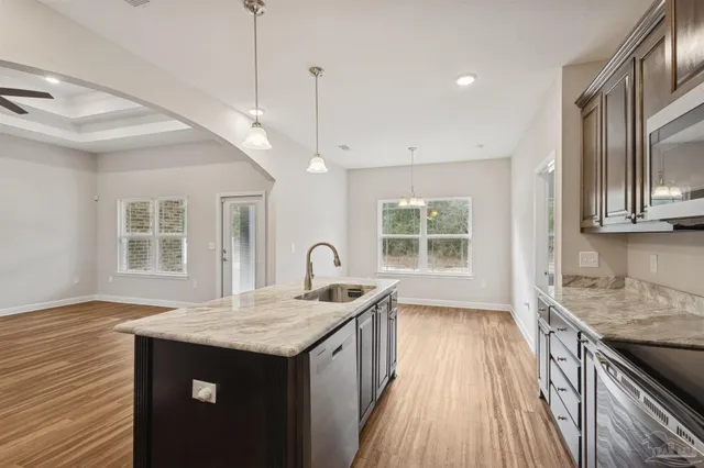 a kitchen with kitchen island granite countertop a sink and wooden floor