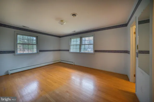 an empty room with wooden floor and windows