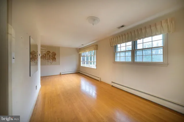 a view of an empty room with a window and wooden floor