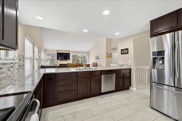 a large kitchen with stainless steel appliances granite countertop a refrigerator and a stove top oven