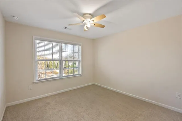 an empty room with a chandelier fan and wooden floor