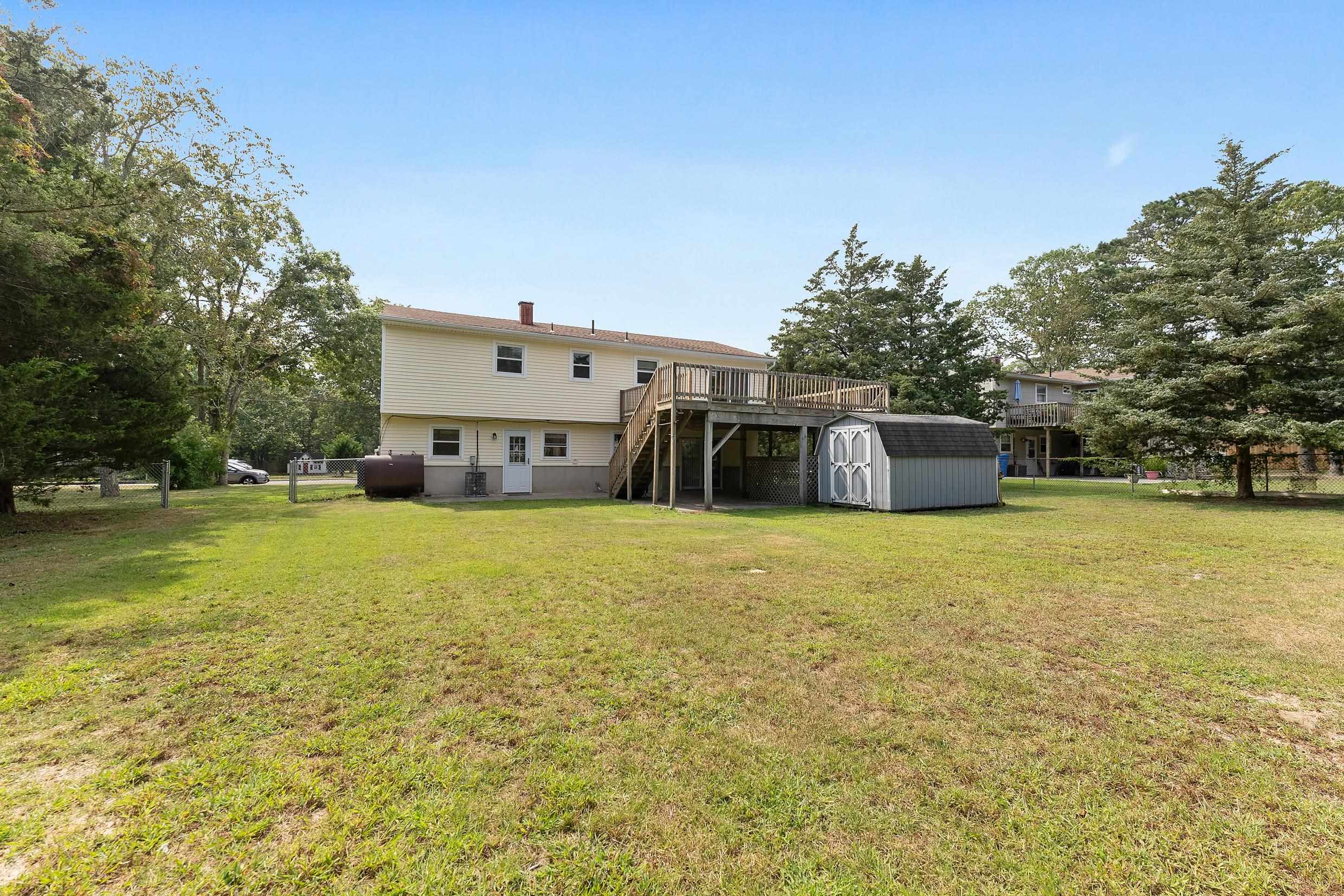 119 Butter Ocean View, NJ 08230 - Photo 27 of 29 a tall yellow house with a big yard and large trees