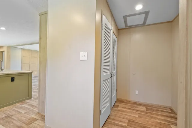 a view of a hallway with wooden floor and a bathroom