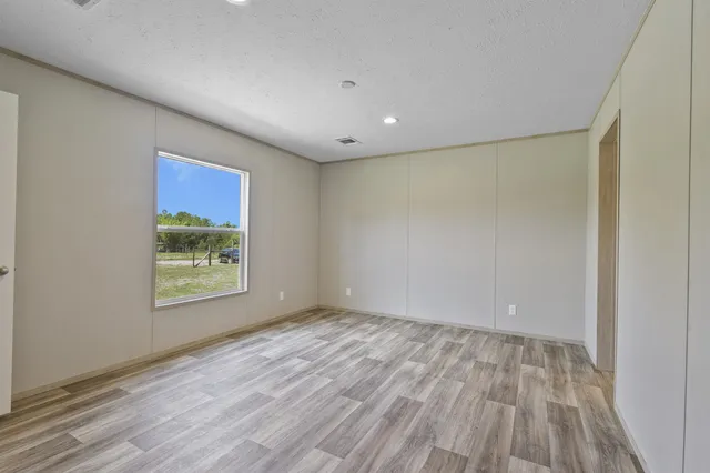 a view of an empty room with a window and wooden floor