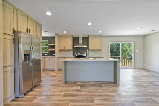 a large kitchen with stainless steel appliances granite countertop a refrigerator a oven a sink and a granite counter tops with a large window