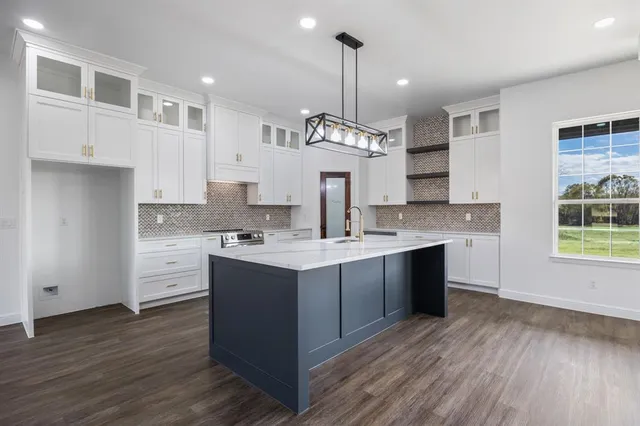 a large kitchen with stainless steel appliances granite countertop a sink stove and wooden floor