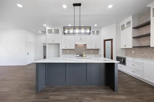 a view of a kitchen with kitchen island a sink stainless steel appliances and cabinets