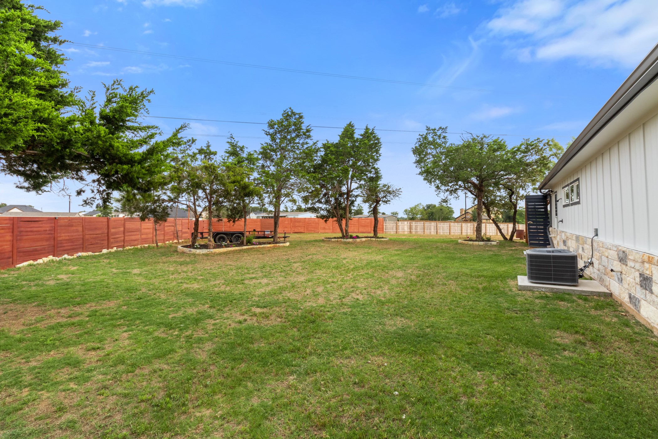 123 Zacate Street Elgin, TX 78621 - Photo 2 of 33 Expansive backyard featuring a manicured lawn, established trees, and a privacy fence