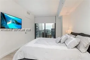 a bedroom with a large bed and a flat tv screen on dresser