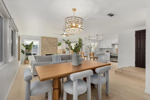 a dining room with wooden floor a chandelier a wooden table and chairs